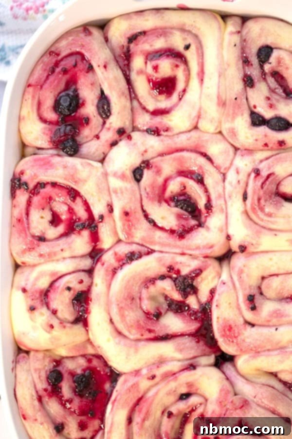 Sweet rolls rising in a white baking dish, ready for baking.