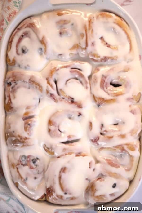 Baked sweet rolls covered with generous lemon icing in a baking dish.