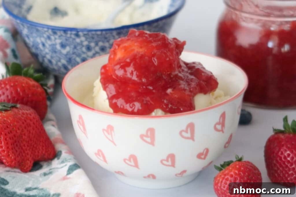 A bowl full of vanilla ice cream topped with homemade Strawberry Sauce, strawberry sauce with frozen strawberries.