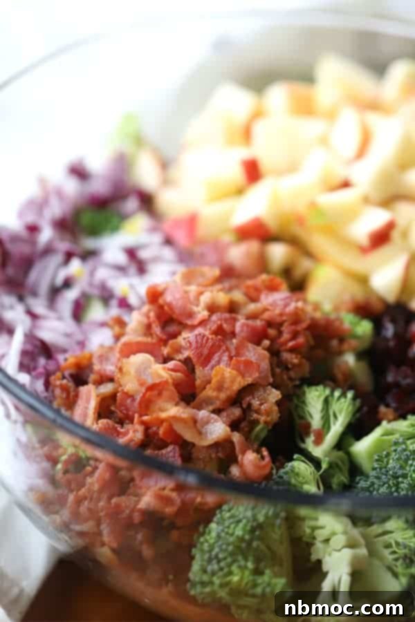 A close-up of the fresh ingredients for broccoli bacon salad in a mixing bowl, ready to be combined with the creamy dressing.
