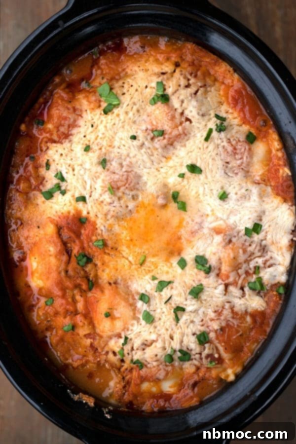 Effortless Slow Cooker Ravioli Lasagna 4 Cooked crockpot lasagna with ravioli, garnished with fresh parsley.