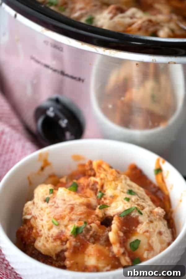Effortless Slow Cooker Ravioli Lasagna 5 A serving of crockpot ravioli lasagna in a white bowl, ready to be enjoyed.