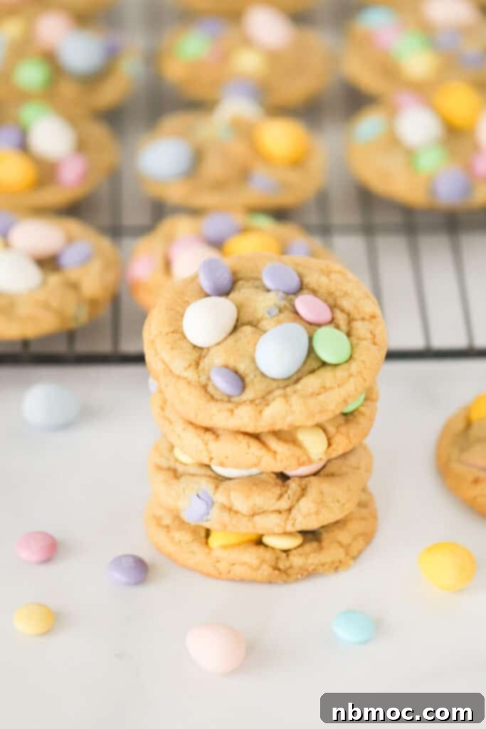 A stack of Cadbury Egg Cookies on a table with a cooling rack full of more cookies in the background. cute mini egg cookie recipe, best mini egg recipes.