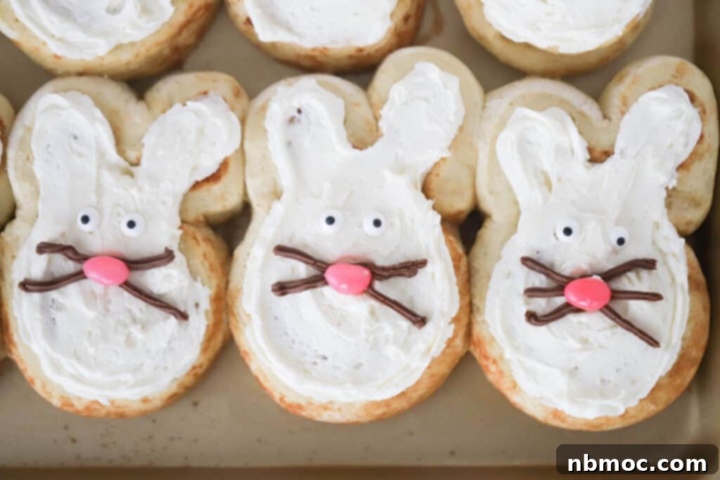 Whimsical Bunny Buns 5 Cinnamon roll bunnies on a baking sheet topped with frosting and decorated with candy and frosting. easter bunny rolls, cinnamon bunnies, bunny biscuits, cinnamon bunny, easter bunny breakfast.