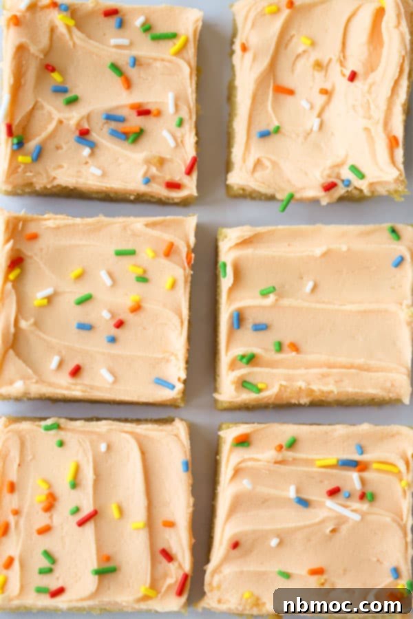 Sunshine Creamsicle Cookie Bars 5 Various orange creamsicle sugar cookie bars artfully arranged, each topped with a delicate swirl of orange frosting and a sprinkle of colorful decorations, ready for enjoyment.
