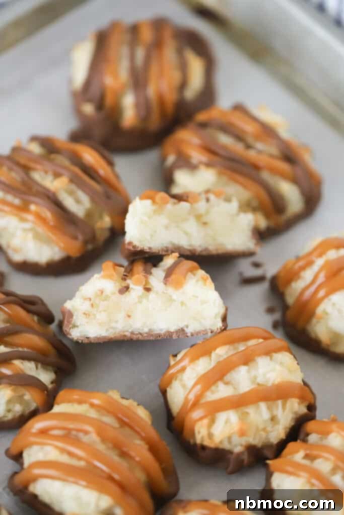 Coconut macaroons with chocolate and caramel drizzle on a baking sheet.