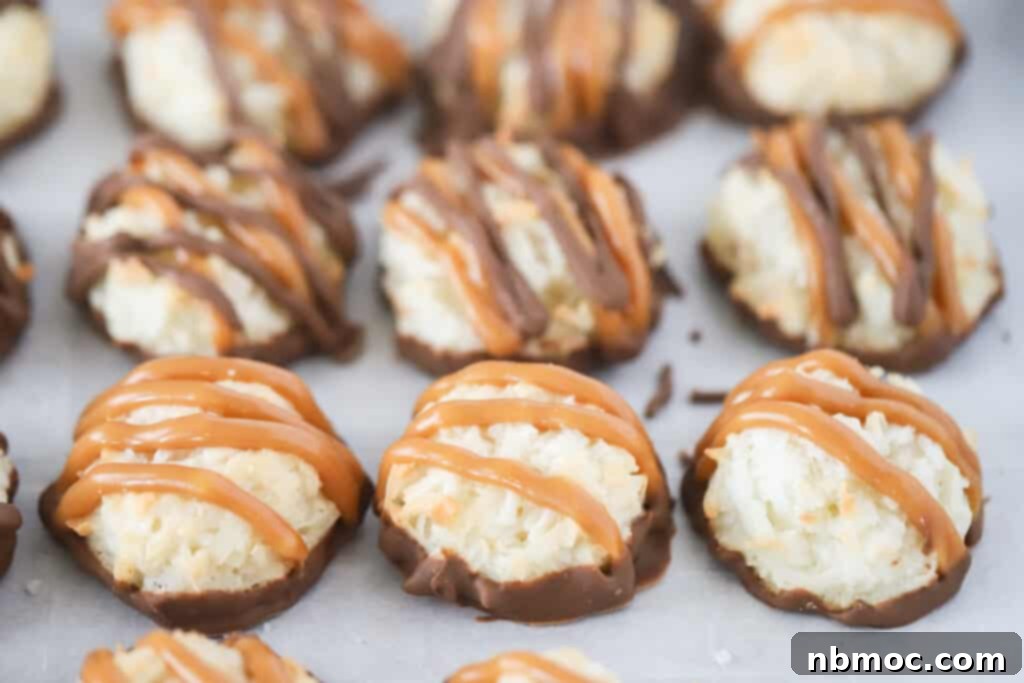 Macaroons dipped in chocolate and drizzled with caramel on a sheet tray.