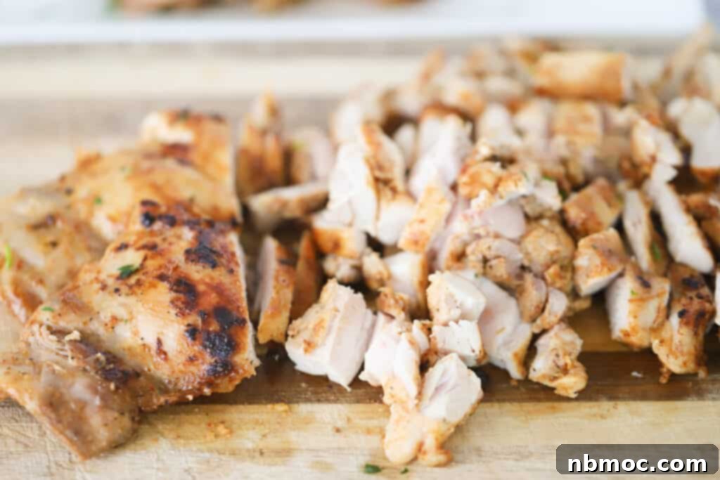 Expertly cooked chicken thigh taco meat being diced on a clean cutting board, ready for taco assembly.