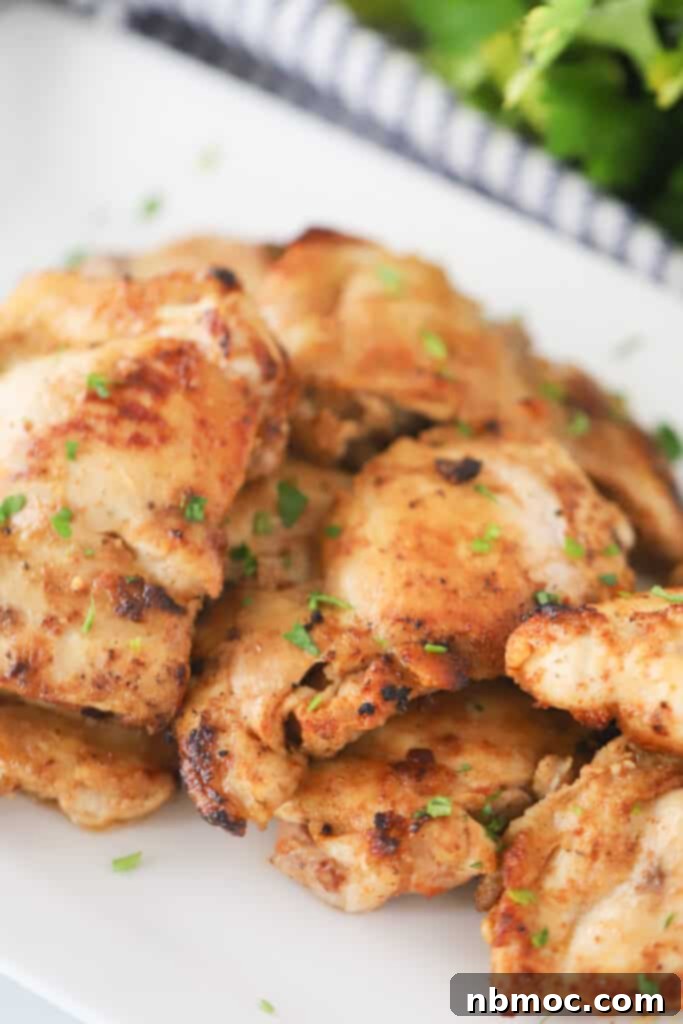 A white plate generously filled with perfectly sauteed, golden-brown chicken thighs, ready to be prepared for this delicious chicken taco recipe.