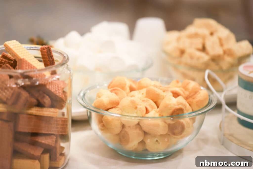 Decadent Chocolate Cascade 5 A table with separate bowls filled with items for dipping into a chocolate fountain, including wafer cookies, cream puffs and marshmallows.