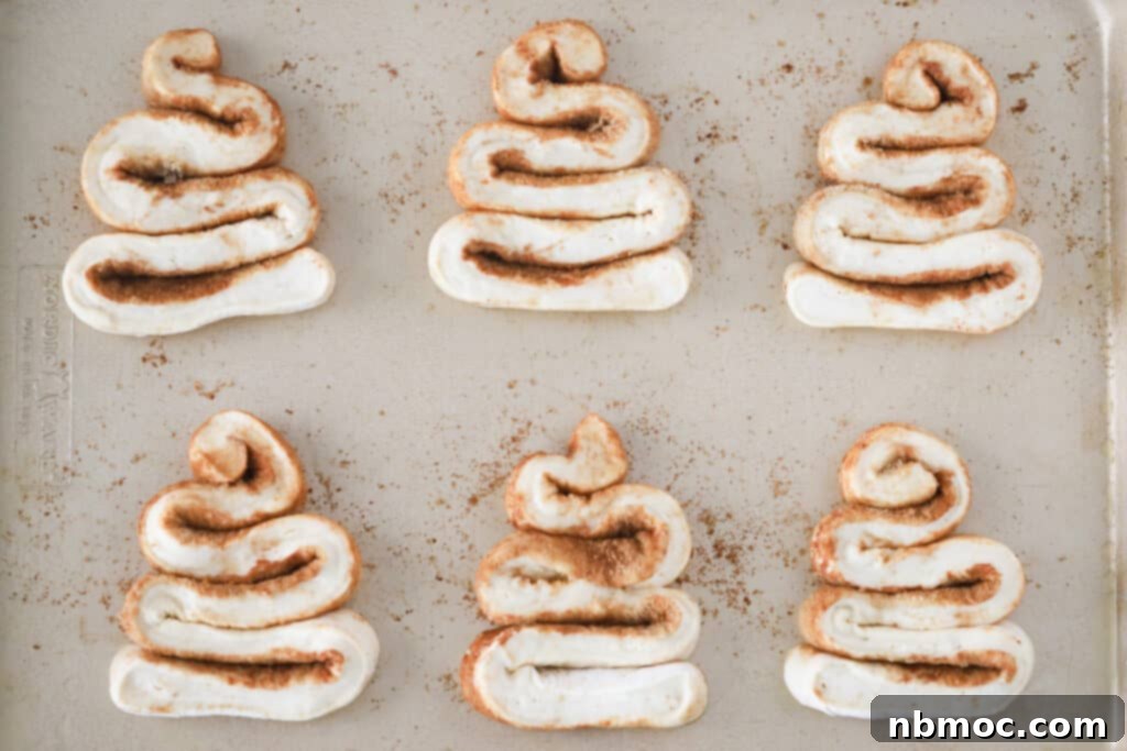 A sheet pan with rows of Christmas Tree Cinnamon Rolls ready to bake in the oven. cinnamon roll Christmas tree. 