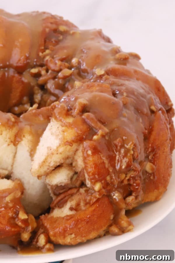 Golden-brown caramel pecan monkey bread, studded with nuts, pulled apart to reveal its gooey interior, a perfect breakfast or brunch treat.