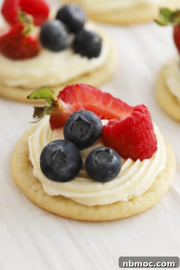 Mini sugar cookie pizzas topped with fresh fruit and cream cheese frosting, a fun and easy dessert idea.