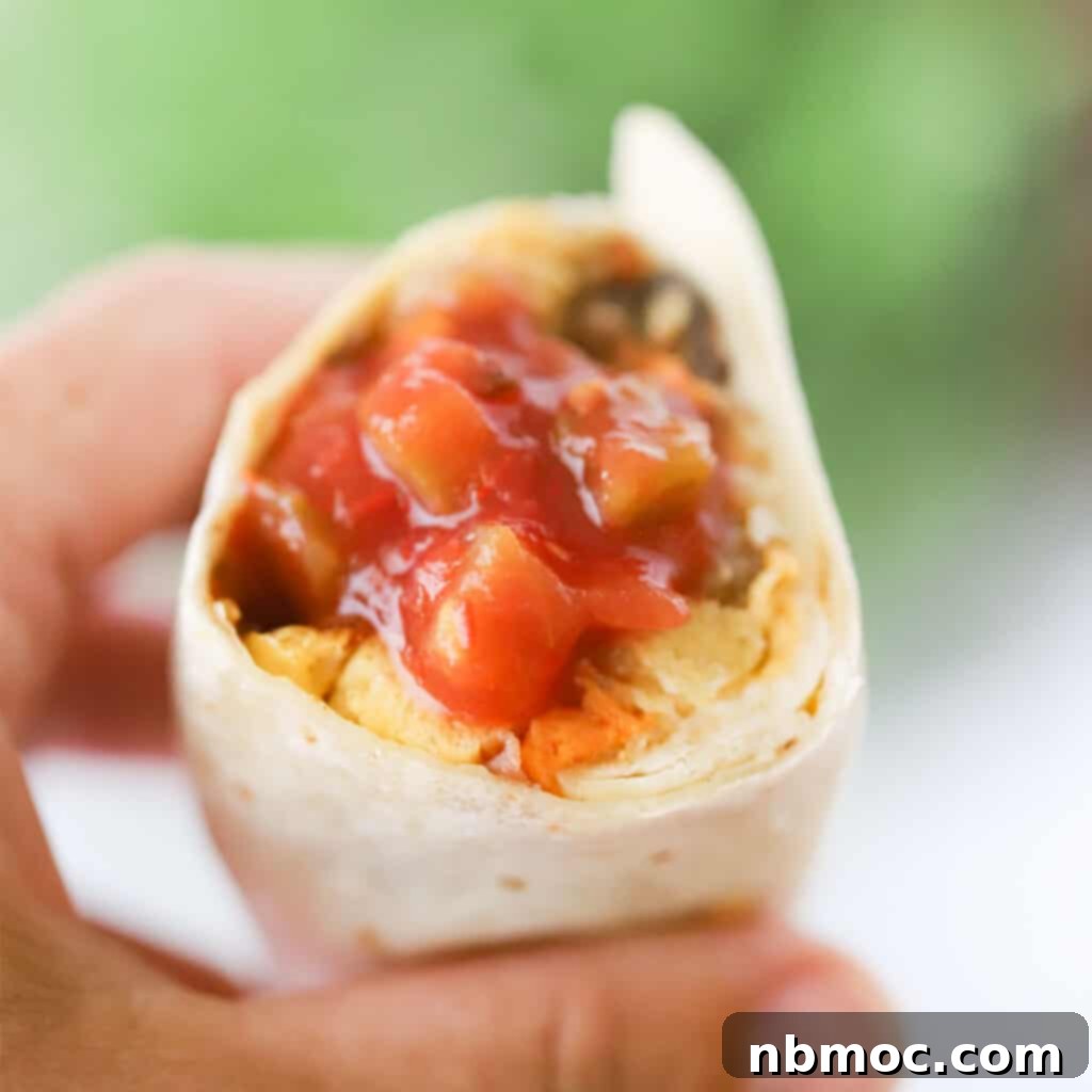 A plate of hearty freezer-friendly breakfast burritos, sliced open to show the fillings.