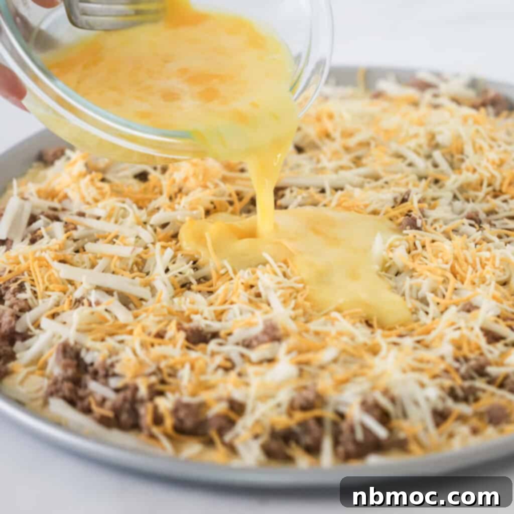 A savory breakfast pizza topped with sausage, hash browns, eggs, and cheese, on a crescent roll crust.
