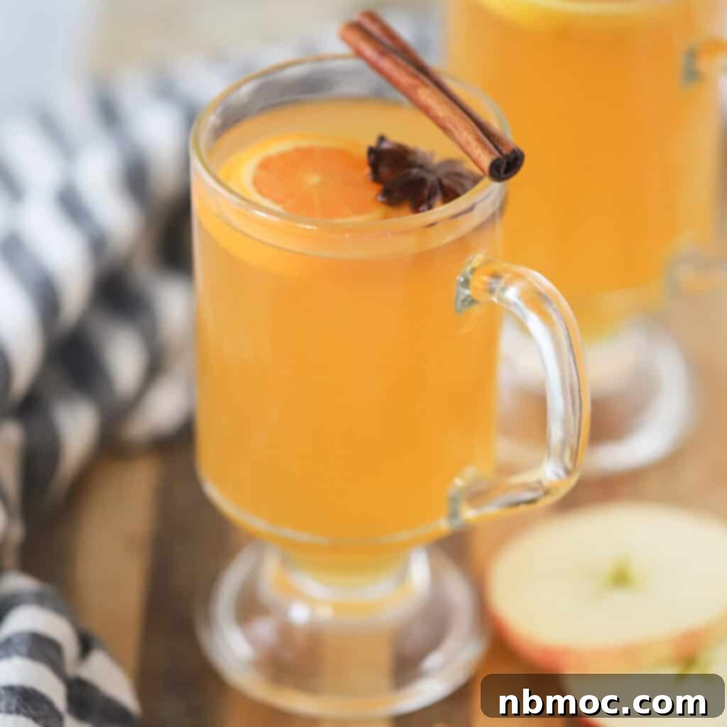 Homemade slow cooker wassail, garnished with orange slices and cinnamon sticks, a cozy holiday drink.