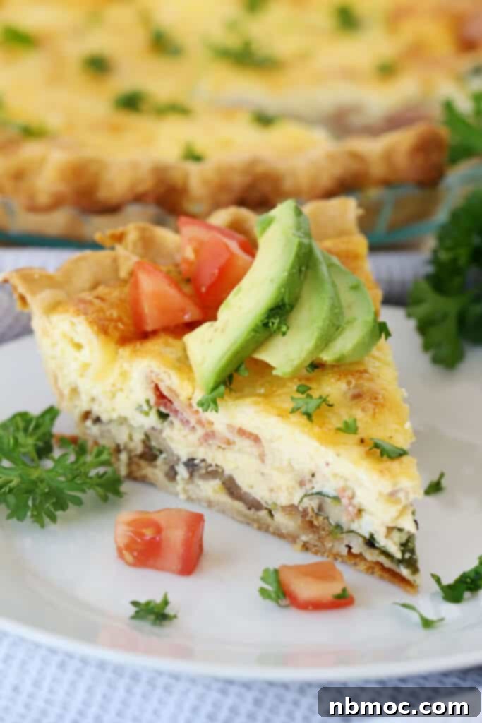 A delicious bacon and mushroom quiche, garnished with avocado and tomato slices, making for a healthy and satisfying breakfast.