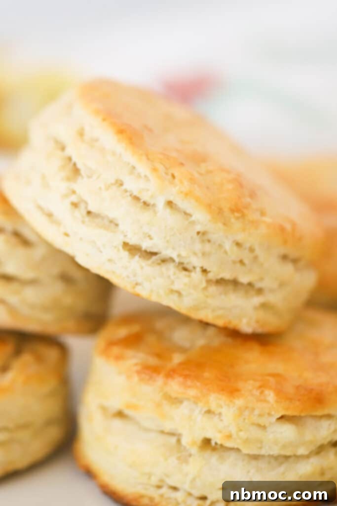 A stack of golden flaky homemade biscuits, fresh from the oven, a classic and comforting breakfast item.