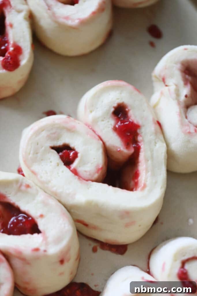 Unbaked raspberry sweet rolls, rising in a baking dish, promising a fluffy and fruity brunch treat.
