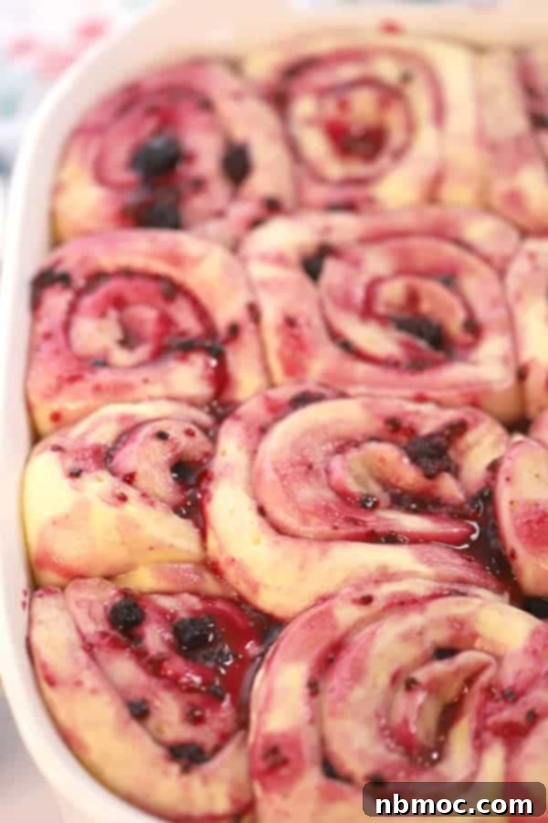 Triple berry sweet cinnamon rolls rising in a baking dish, promising a flavorful and fruity brunch experience.