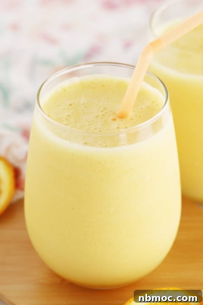 A tall glass of frothy Orange Julius with a straw, a perfect refreshing drink for brunch.