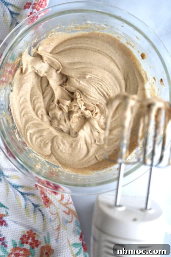 Homemade whipped cinnamon honey butter being mixed with an electric hand mixer, showcasing its creamy texture.