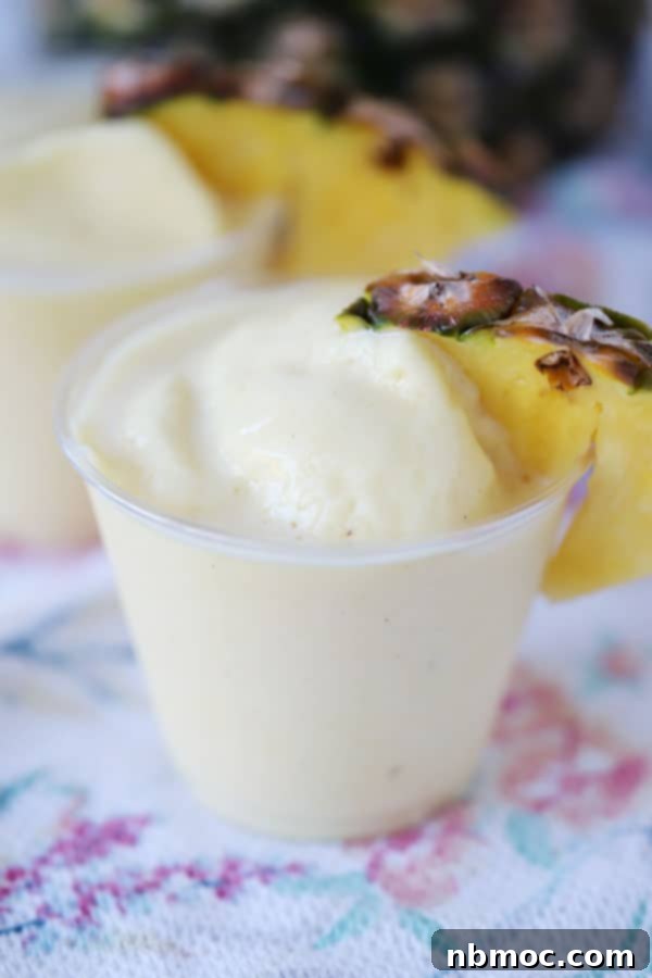 Homemade Dole Whip in a glass, with a cherry on top, a refreshing and creamy dessert or drink.