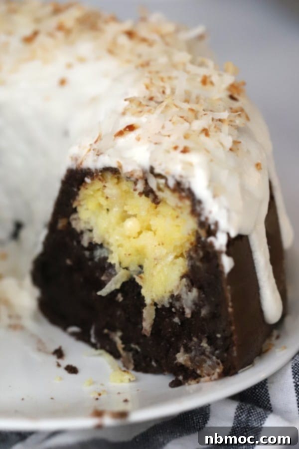 A slice of coconut-filled chocolate bundt cake, showing its creamy white chocolate and coconut center, a delightful dessert.