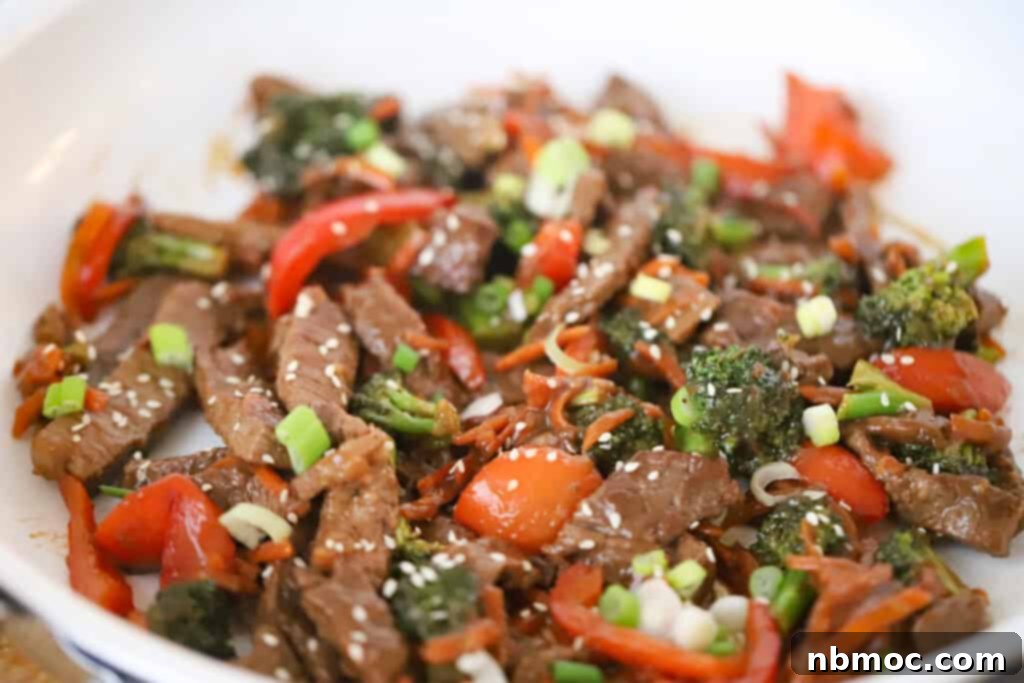 Korean Beef Stir Fry in a skillet, beautifully garnished with sliced green onions and sesame seeds, ready to be served.