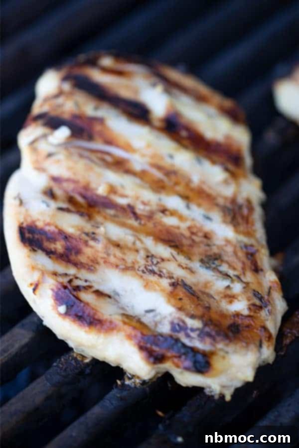 Flavorful Rosemary Garlic Chicken Breast Marinade 3 Grilled rosemary chicken breast sizzling on a hot outdoor grill, showing perfect char marks.