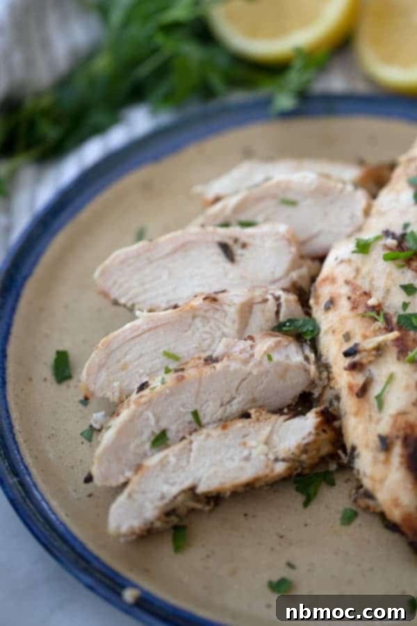Flavorful Rosemary Garlic Chicken Breast Marinade 4 Grilled rosemary garlic chicken breasts, perfectly sliced on a white plate, ready to serve.