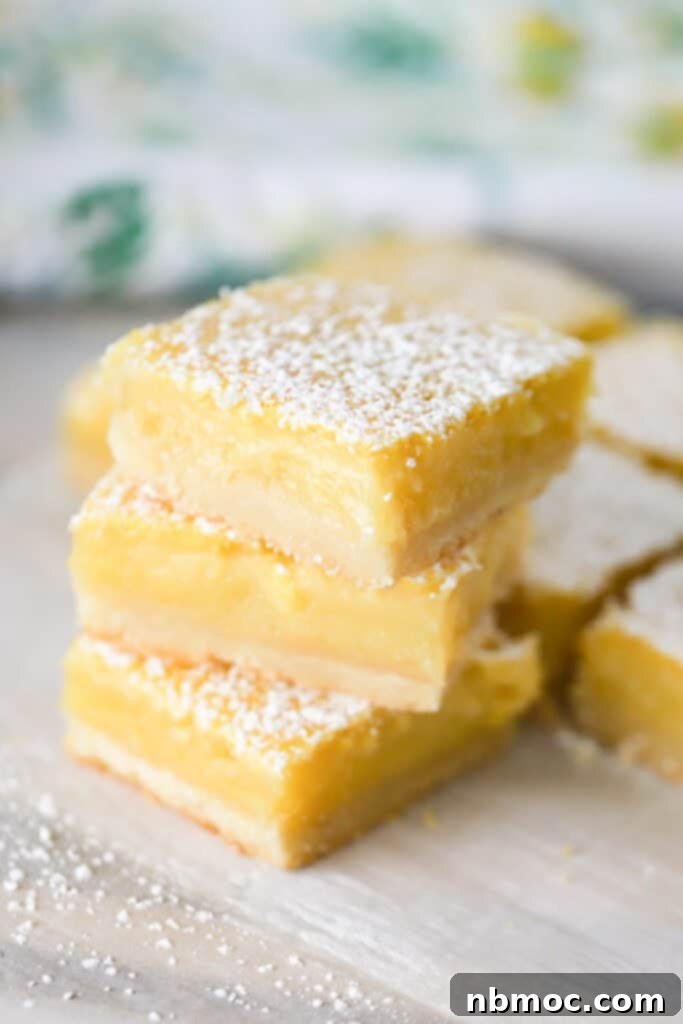 A stack of easy lemon bars on a tabletop, dusted with powdered sugar. 
