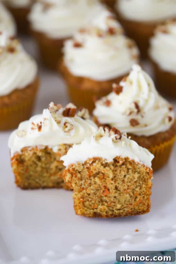 Simple Carrot Cake Cupcakes on a serving plate topped with cream cheese frosting and chopped nuts.