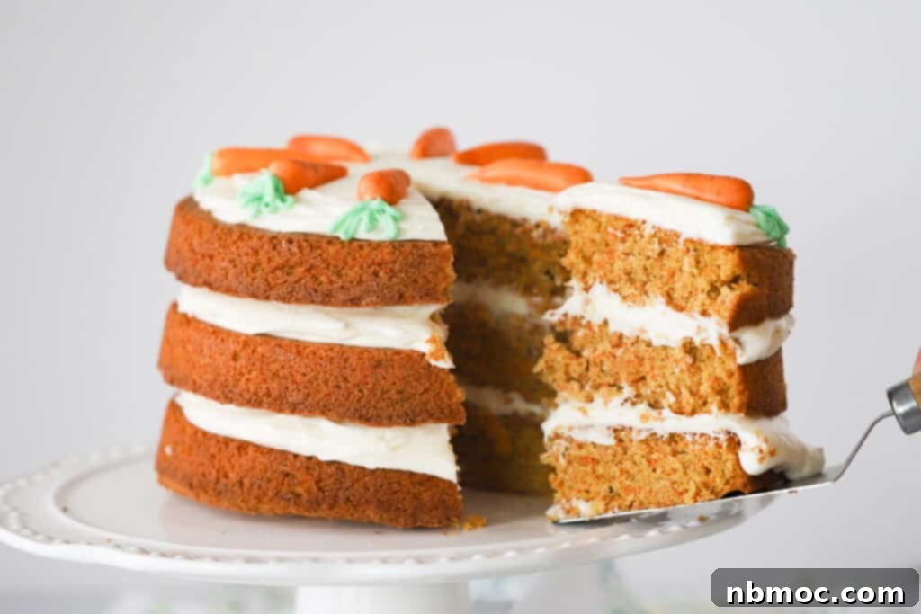 Ultimate Carrot Cake 7 A three-tiered Carrot Cake with cream cheese frosting on top of the cake and in between the layers. A slice is being removed using a cake server.