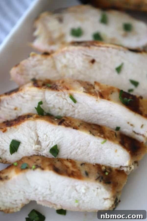 Sliced Honey Mustard Grilled Chicken on a serving platter, garnished with fresh herbs.