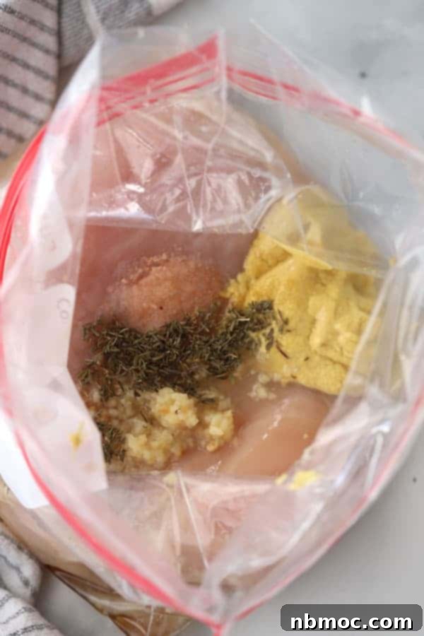 Raw chicken breasts marinating in a honey mustard sauce inside a freezer bag.