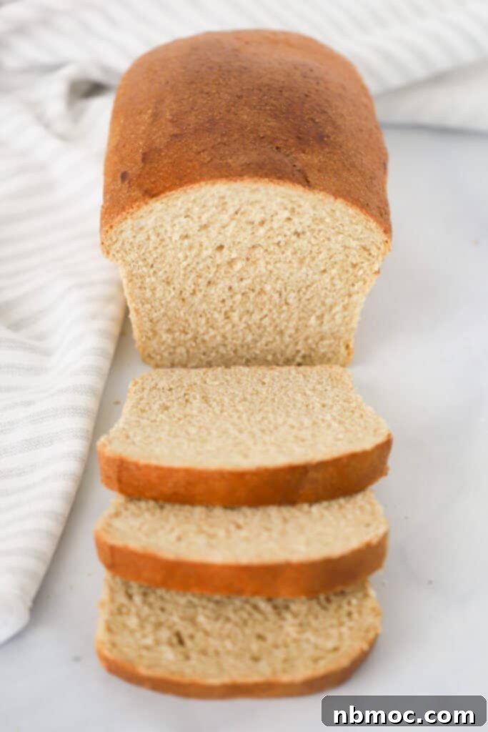 A golden brown loaf of homemade Whole Wheat Bread resting on a rustic wooden cutting board, with several perfect slices laid beside it.