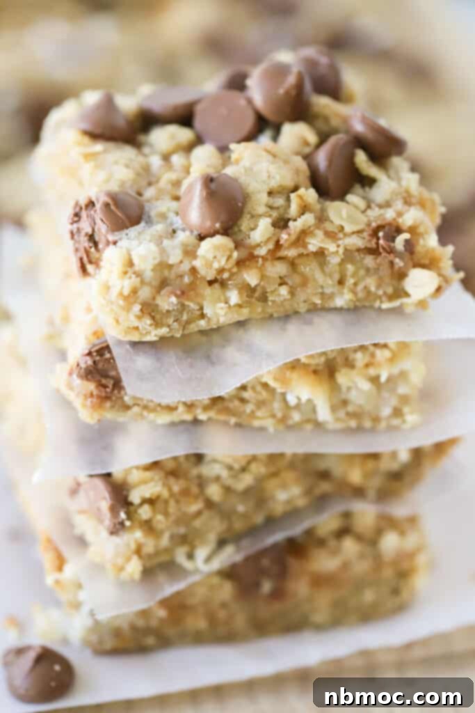 A stack of seven layer magic cookie bars topped with chocolate chips.