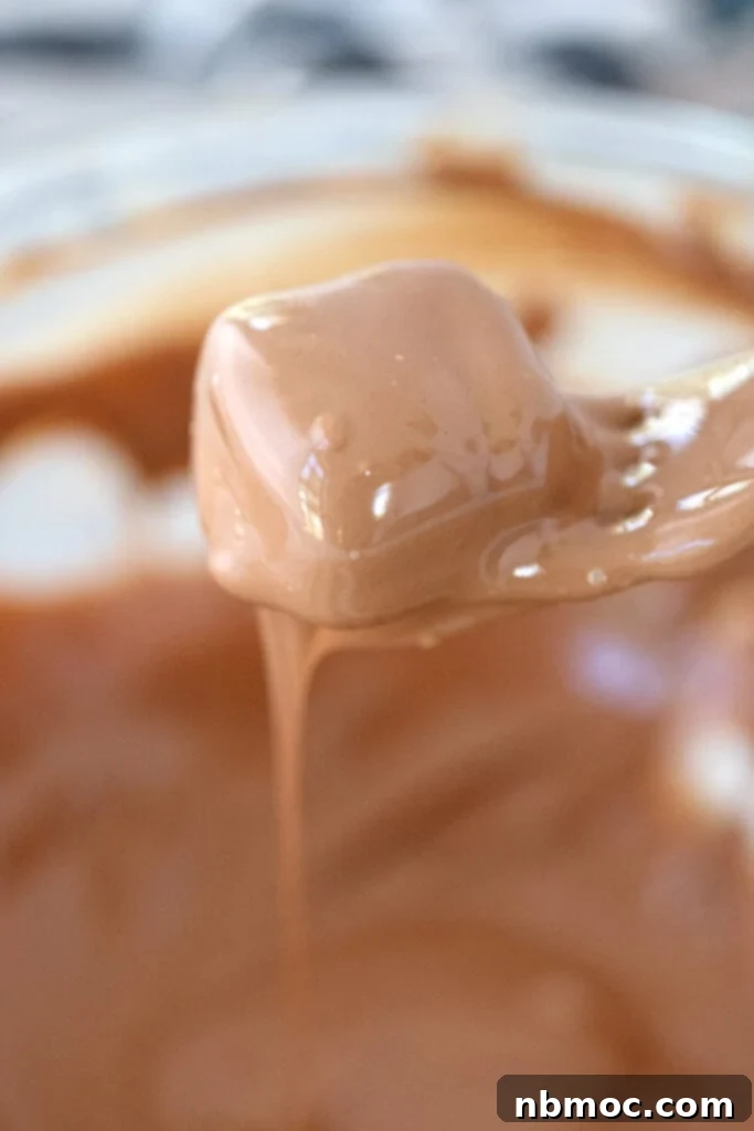 A chocolate covered caramel candy on a fork being hand dipped.