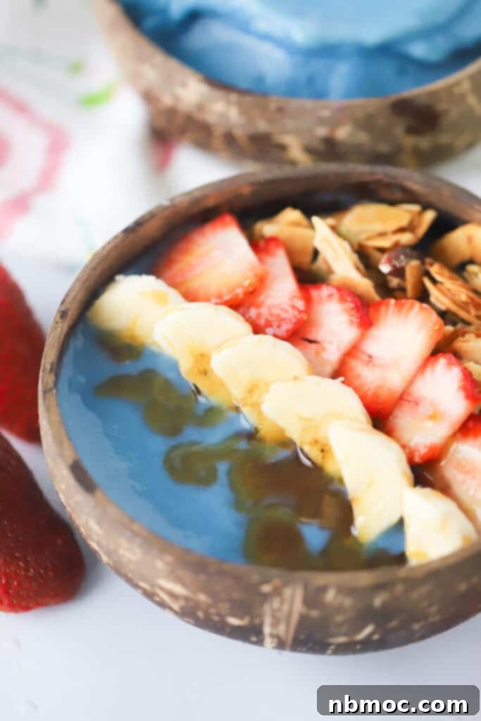 A vibrant blue spirulina smoothie bowl topped with fresh berries and coconut, a healthy blue food recipe.