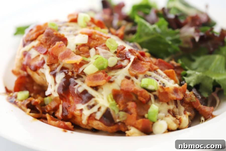 A plate with a serving of Monterey Chicken topped with bacon and BBQ sauce, along with a side salad.