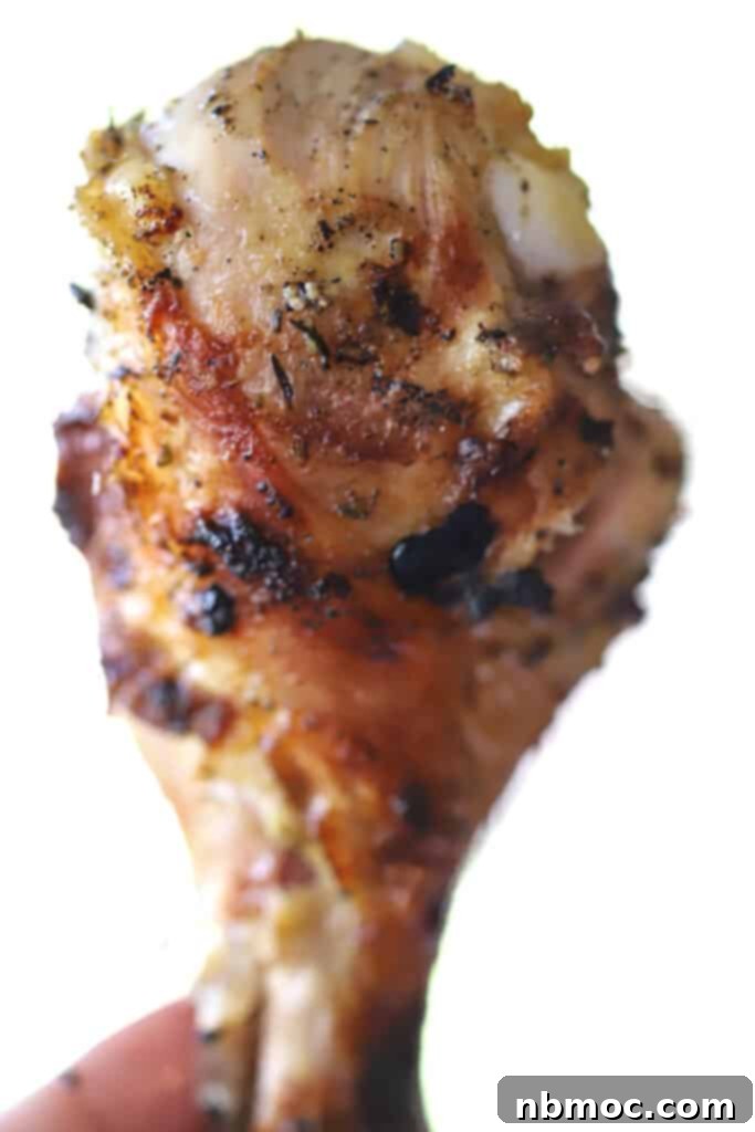 A hand holding a crispy chicken drumstick.