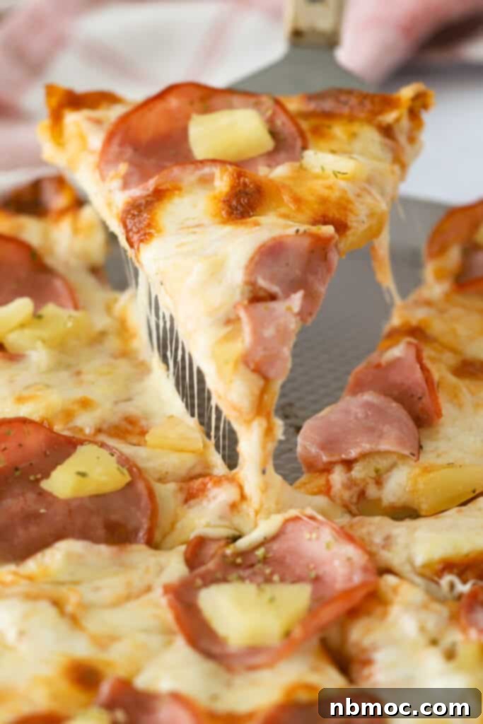 Best Hawaiian Pizza Recipe 2 A pizza pan with a hawaiian pizza topped with canadian bacon and pineapples.