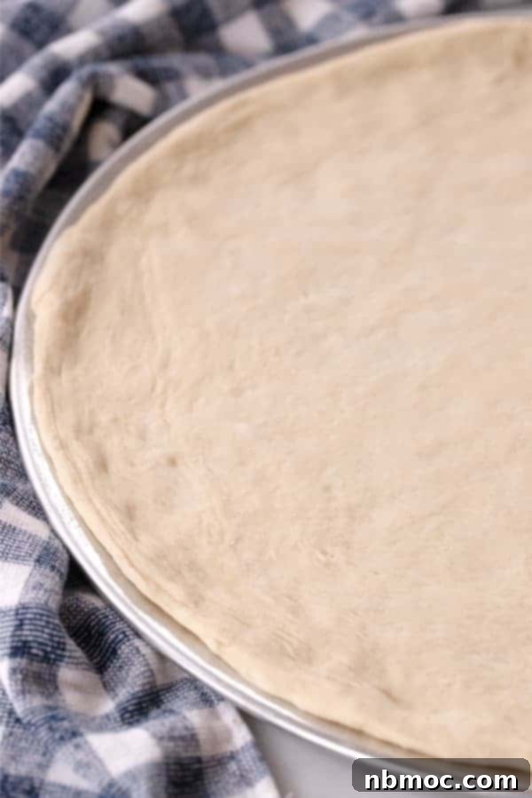 Best Hawaiian Pizza Recipe 4 Fresh pizza dough stretched onto a round pizza pan ready to top.