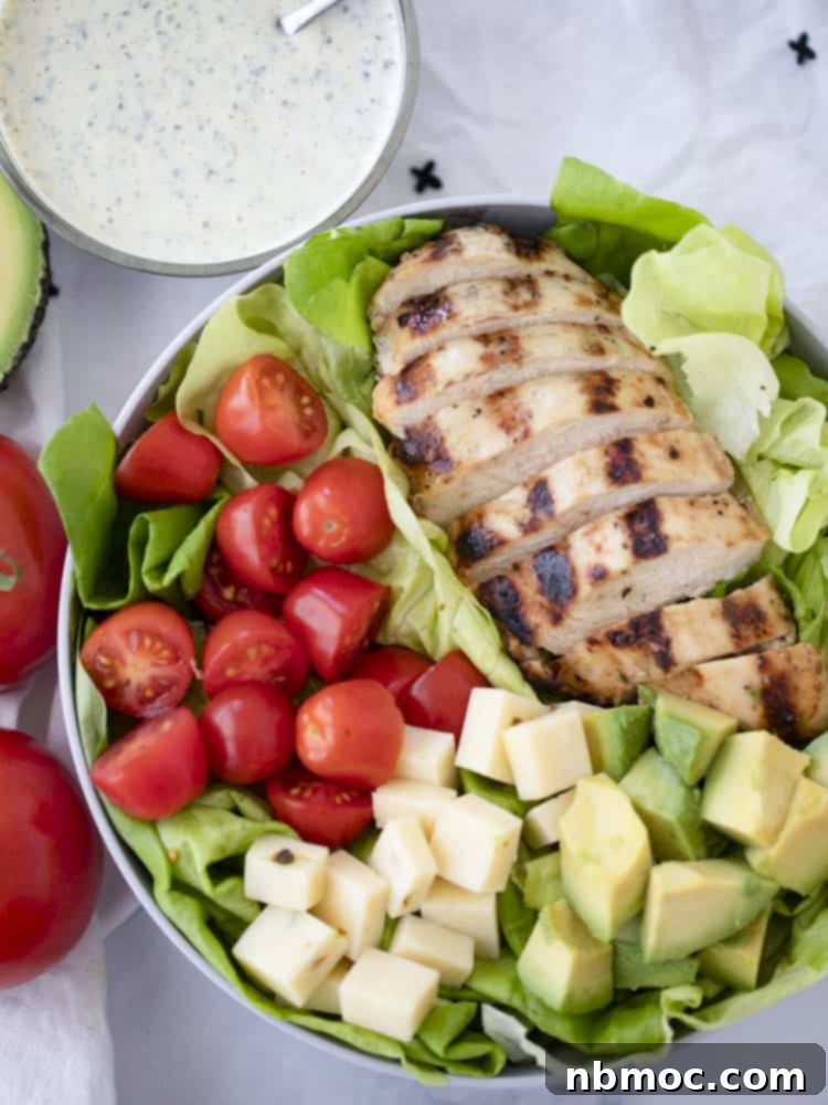 Healthy grilled chicken salad recipe in a bowl with a side of pesto ranch dressing, grilled chicken breast with salad.