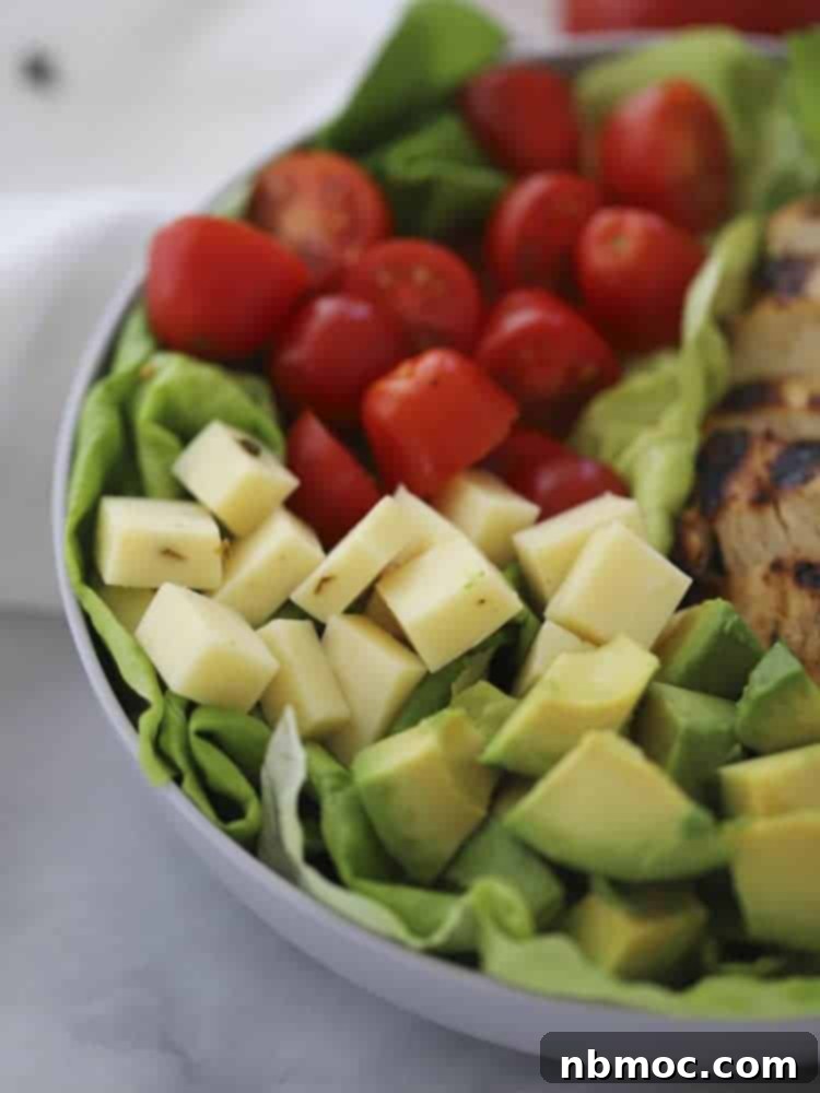 Grilled chicken salad with ranch pesto dressing, showing pepperjack cheese, tomatoes, avocado, and lettuce.