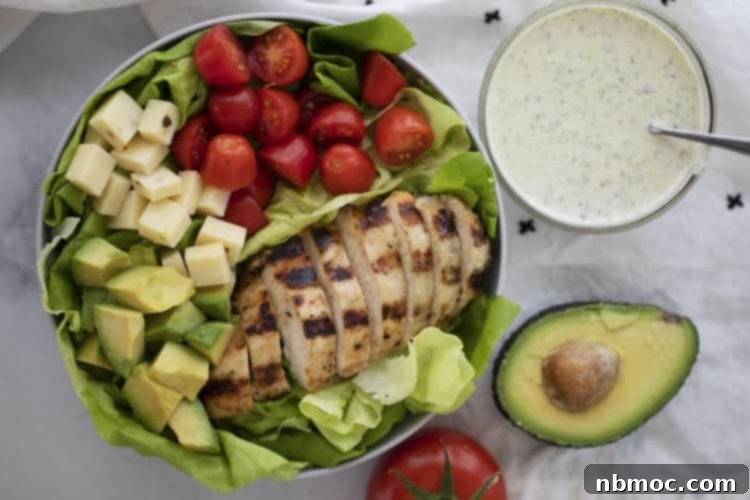 grilled chicken salad with lettuce, tomatoes, avocado, cheese, and pesto ranch salad dressing.