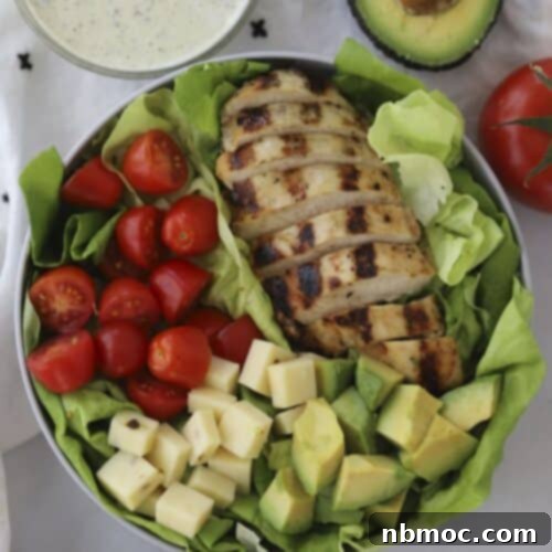Healthy grilled chicken salad in a bowl with a side of pesto ranch.