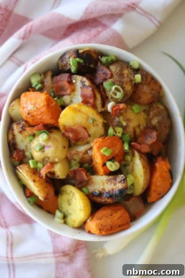 A white bowl full of grilled potato salad made with grilled potatoes, bacon, green onions and dressing. German style potato salad.