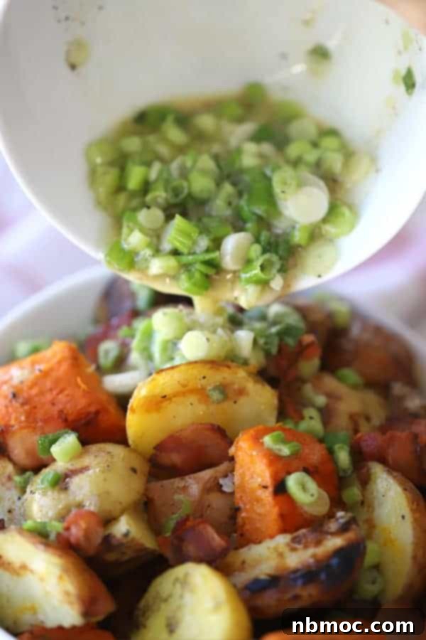 A bowl of grilled potato salad without bacon, with the vinaigrette being poured over the top.